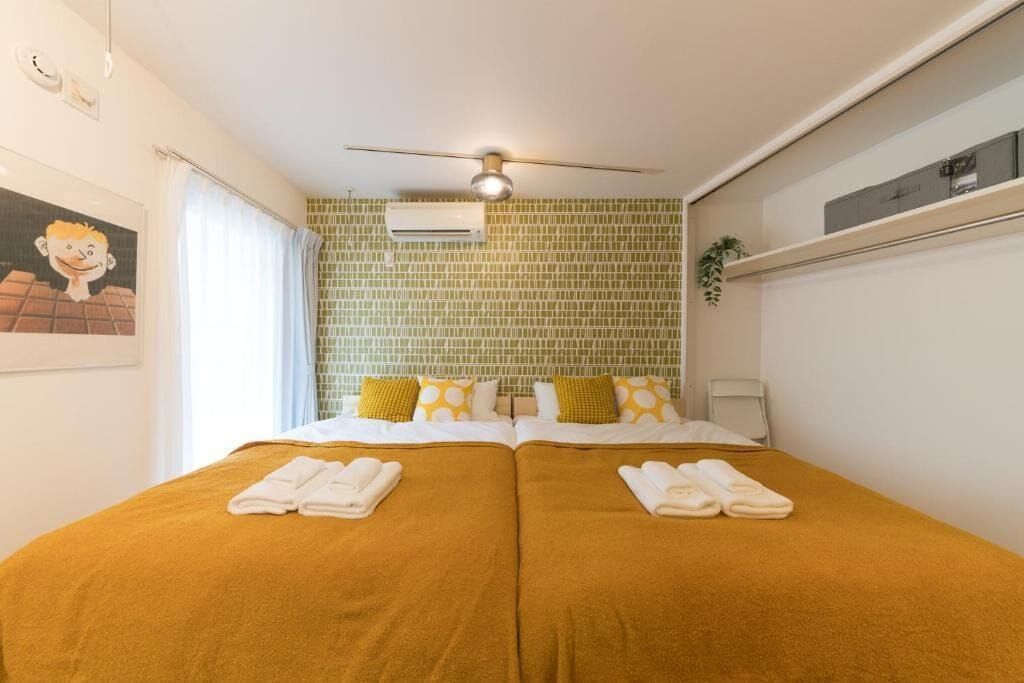 Een tweepersoonsbed met twee sets handdoeken, een plafondventilator, een airconditioner en een foto aan de muur.