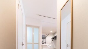 Un estrecho pasillo con piso de madera que conduce a una habitación con cama y ventana.