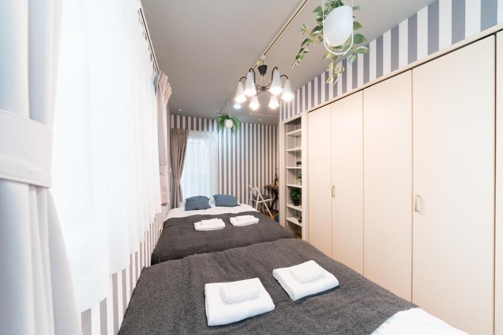 Een hotelkamer met twee bedden, een garderobe, een hangende plant en een kroonluchter.