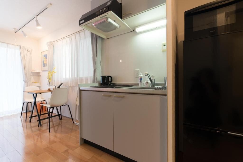 A compact kitchen with a black refrigerator, a coffee maker, and a sink.