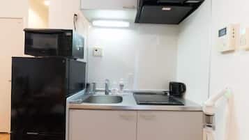 Une cuisine de taille réduite, équipée d’un réfrigérateur noir, d’un four à micro-ondes, d’une cuisinière et d’un évier.