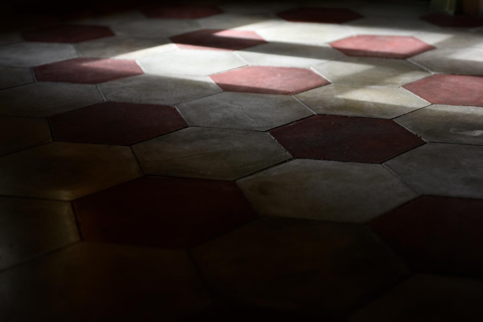 A floor with a geometric pattern of hexagonal tiles in varying shades of brown and beige.
