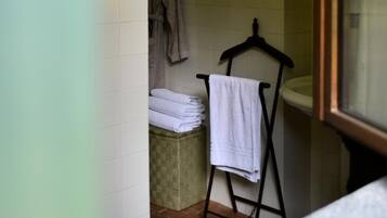 Een badkamer met een handdoekhouder, een opgevouwen badjas en een klein krukje.