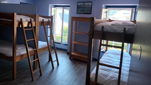 Una habitación con literas, escaleras de madera y una ventana con vistas a la montaña.