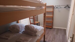 Una litera con escalera de madera, una silla y una estantería de madera con perchas.
