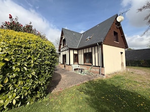 A traditional half-timbered house with a sloped roof, a satellite dish, and a paved entrance. - Les Buissons (st pierre le vieux)