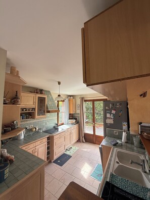 Eine Küche mit Holzschränken, einer gefliesten Spritzschutzwand und einem eingebauten Backofen.
