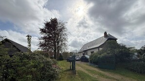 Propiedad rural con una casa, un coche y una reja.