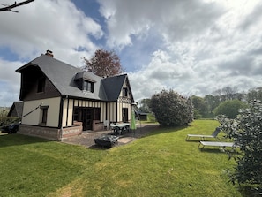 A two-story house with a sloped roof, a brick foundation, and a large front lawn. - Les Buissons (st pierre le vieux)