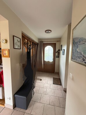 A hallway with a bench, a door with a window, and a staircase. - Les Buissons (st pierre le vieux)