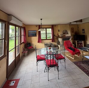 Ein Essbereich mit Glastisch und Stühlen, einem Kamin und einem Fernseher in einem Wohnzimmer.