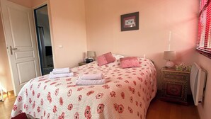 Un dormitorio con cama, mesitas de noche, radiador y puerta.