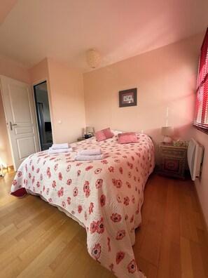 Ein Schlafzimmer mit einem Bett, Nachttischen, einem Heizkörper und einer Tür.