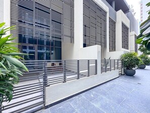 A modern building with large windows, a metal railing, and potted plants. - Chic 1BR Duplex in The Sterling | Business Bay (Dubai)