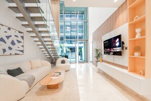 Un salon moderne avec un canapé, une table basse, un téléviseur et un escalier.