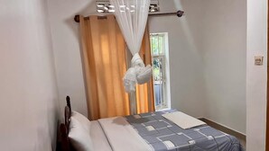 A bedroom with a bed, a wooden nightstand, a window with curtains, and a mosquito net. - SKY LIGHT VILLA (Kigali)