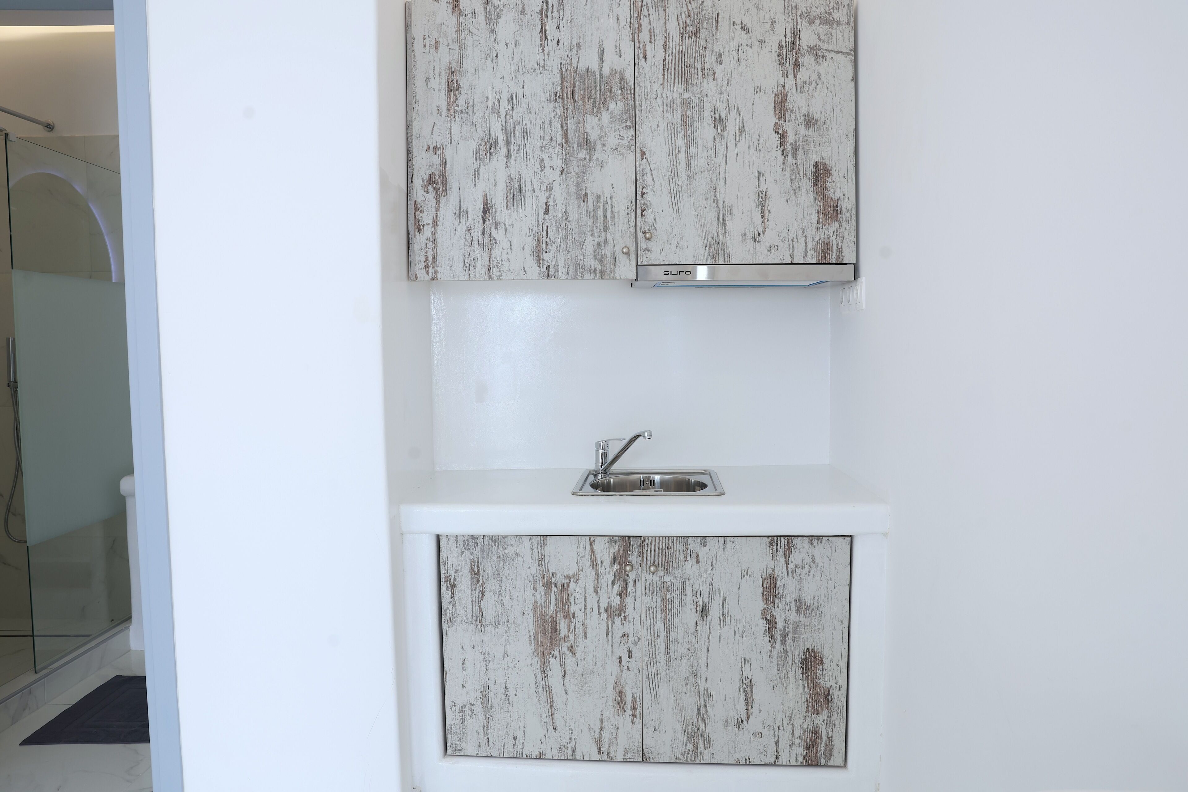 Une salle de bain avec un meuble-lavabo blanc, un évier et un espace douche.