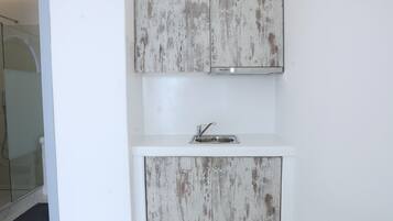 Une salle de bain avec un meuble-lavabo blanc, un évier et un espace douche.