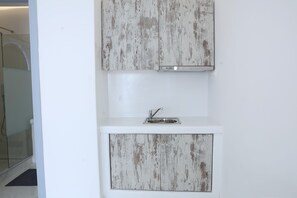 Un baño con tocador blanco, lavamanos y zona de ducha.