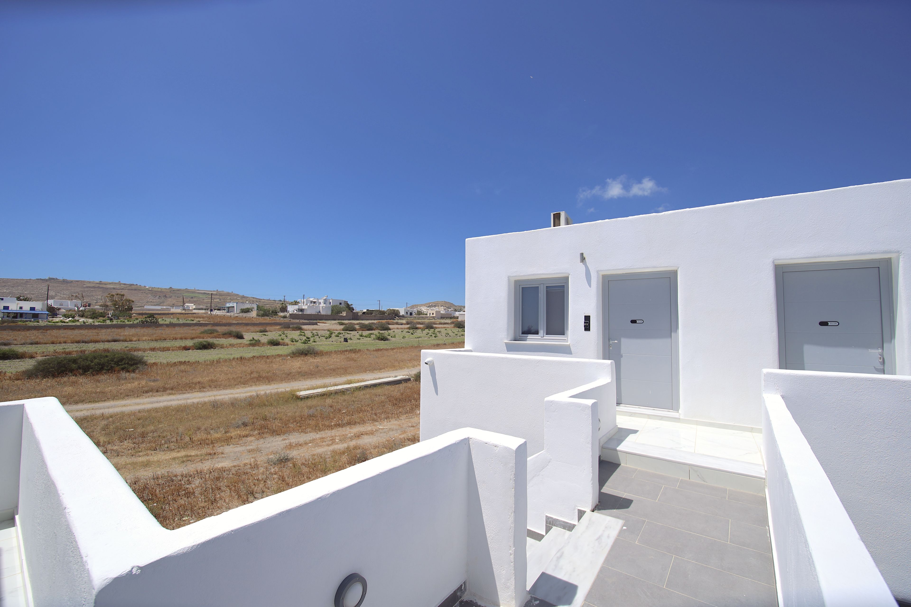 A modern white building with a flat roof, a visible door, and a window.