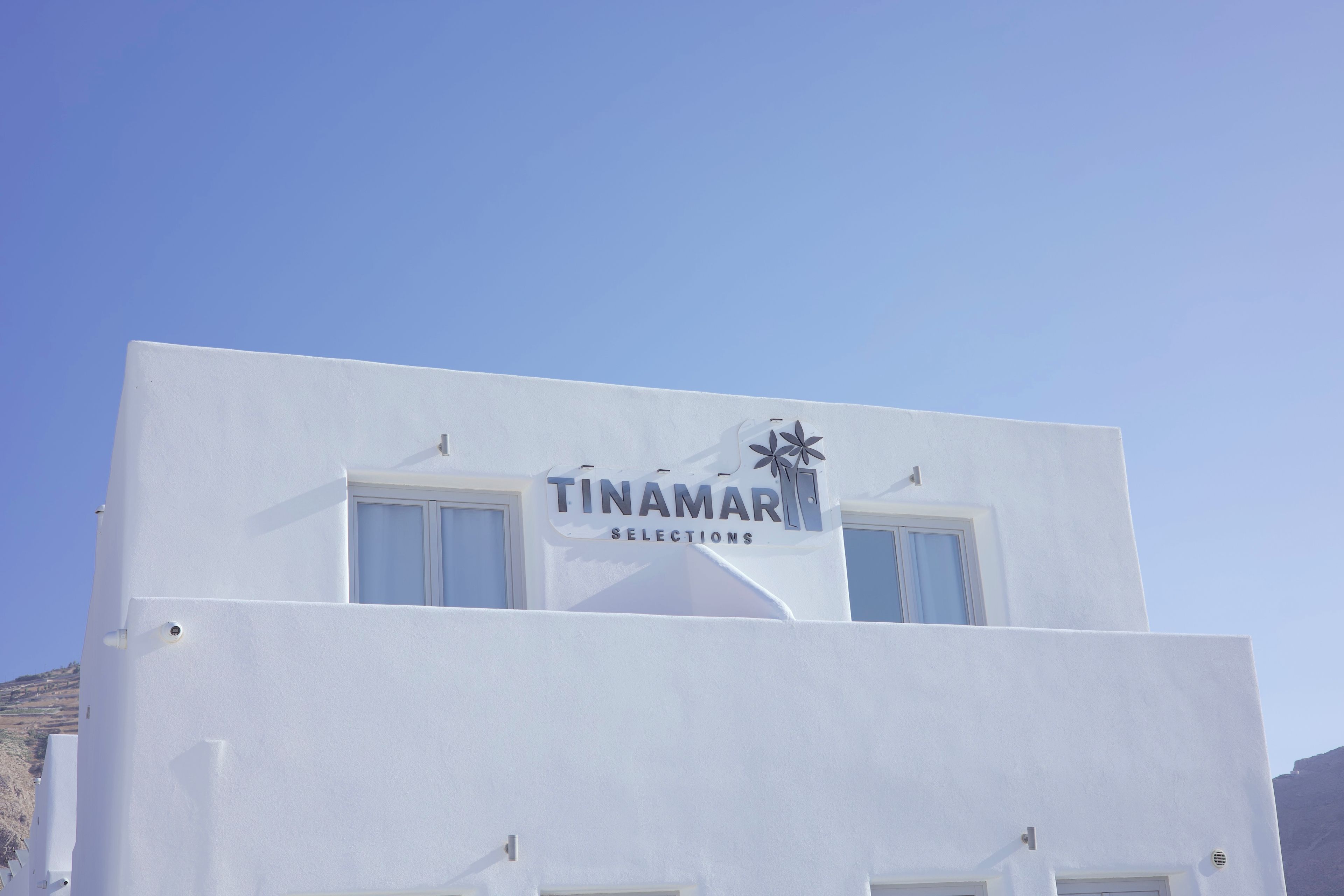 A white building with a sign that reads 'TINAMAR SELECTIONS' and a palm tree logo.
