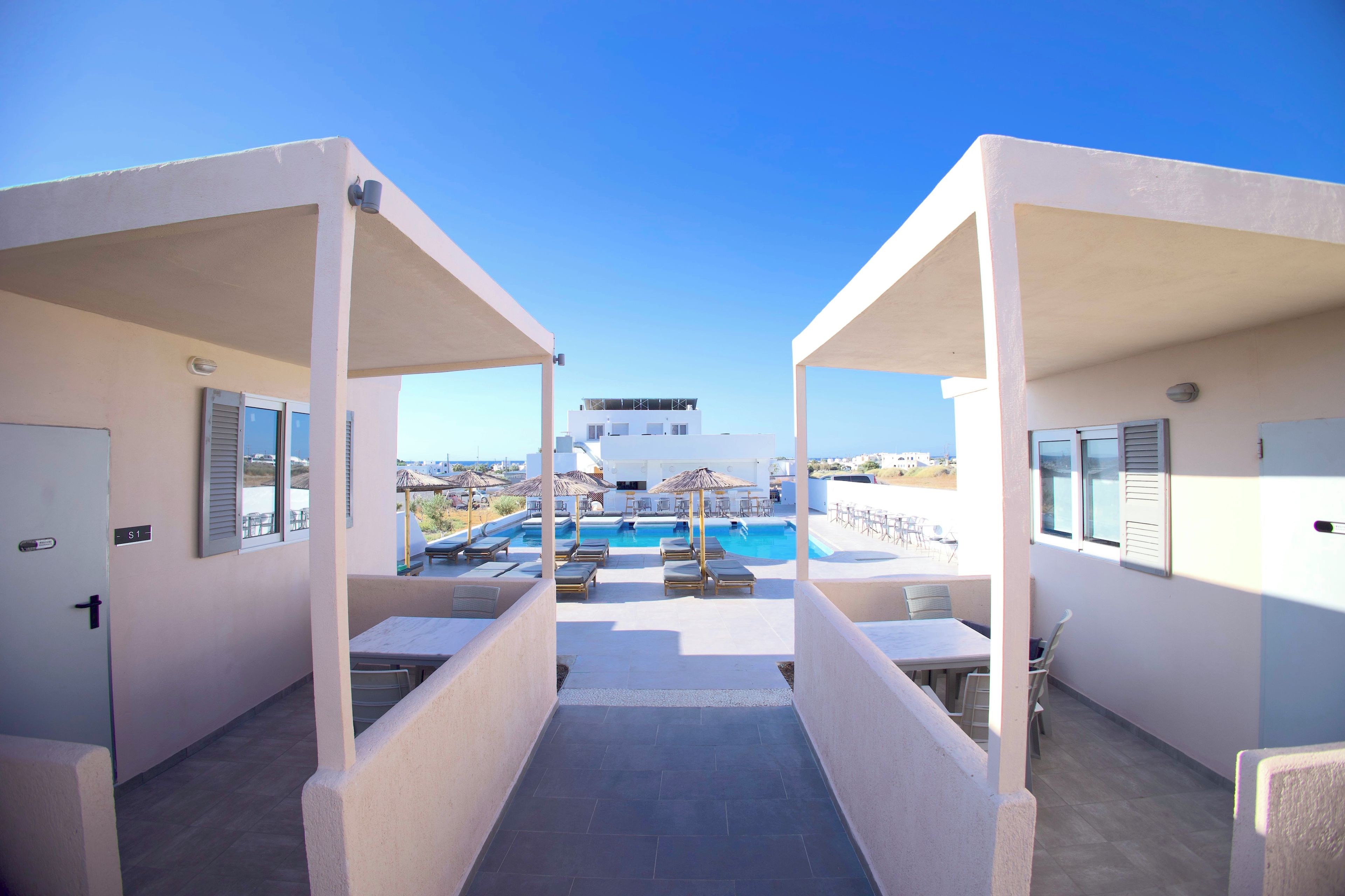 Un balcón moderno de hotel con piscina, sillones de descanso y vista despejada del paisaje urbano.