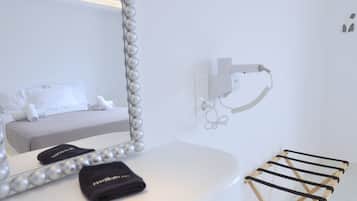 Una habitación de hotel con cama, espejo de marco perlado, toalla y secador de pelo en la pared.