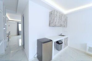 A modern kitchen with a built-in refrigerator, a sink, and a trash bin. - Tinamar Selection (Santorini)