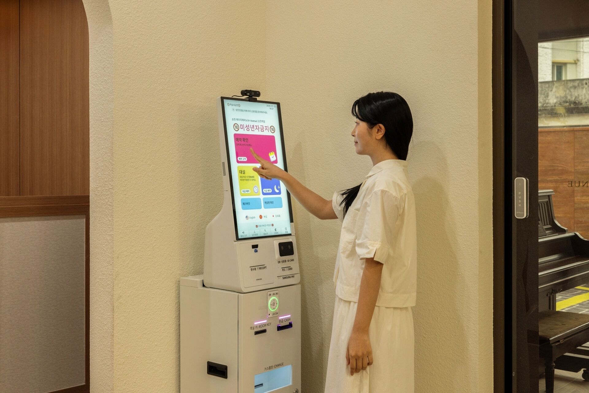 Una persona interactuando con un quiosco digital en el vestíbulo de un hotel.