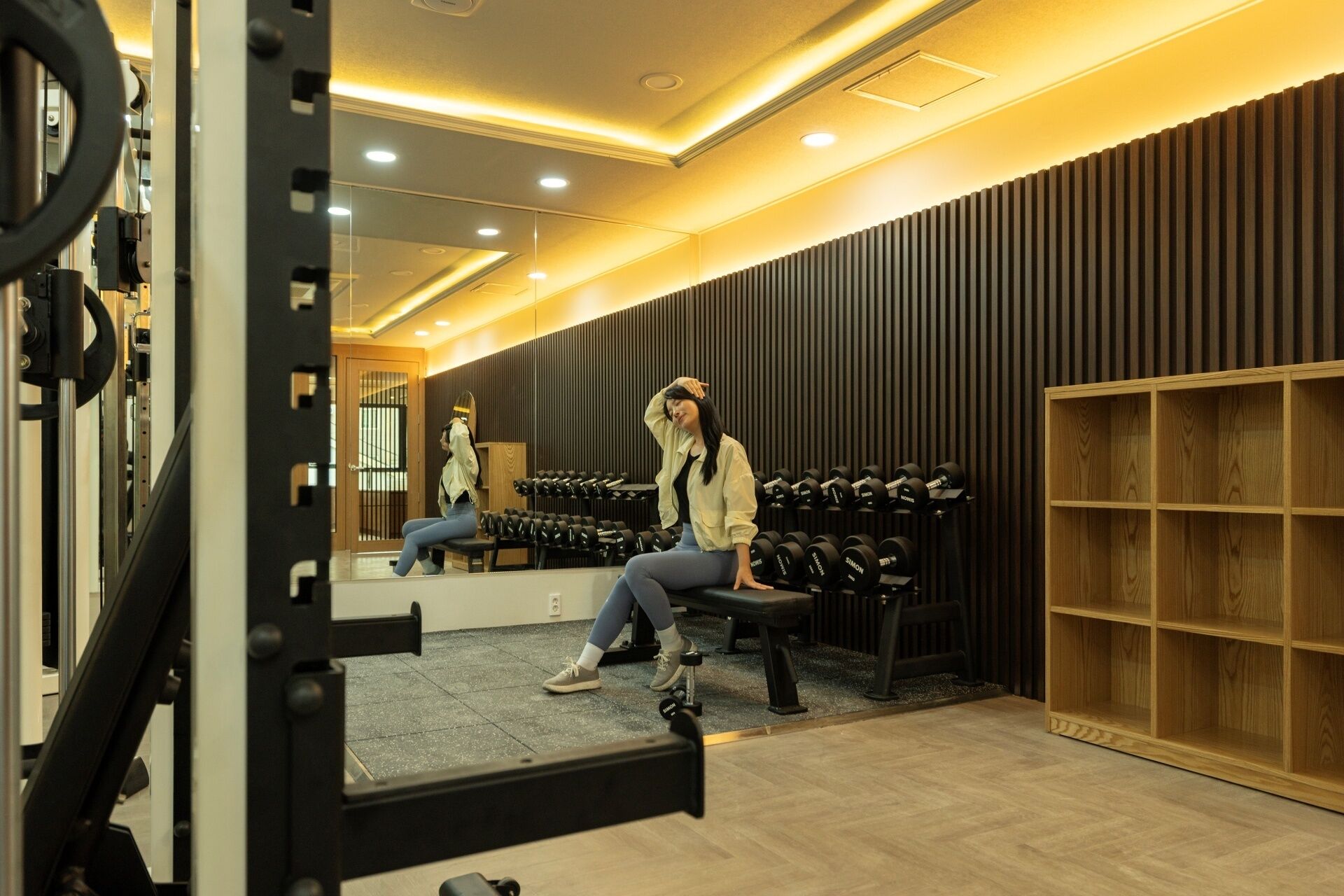 A gym with weightlifting equipment, a bench, and a mirror.