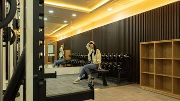 A gym with weightlifting equipment, a bench, and a mirror.