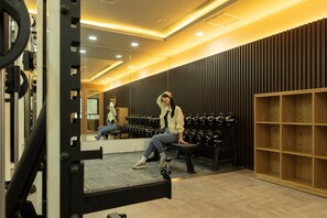 A gym with weightlifting equipment, a bench, and a mirror.