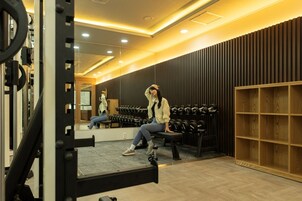 Un gimnasio con equipo de levantamiento de pesas, una banca y un espejo.