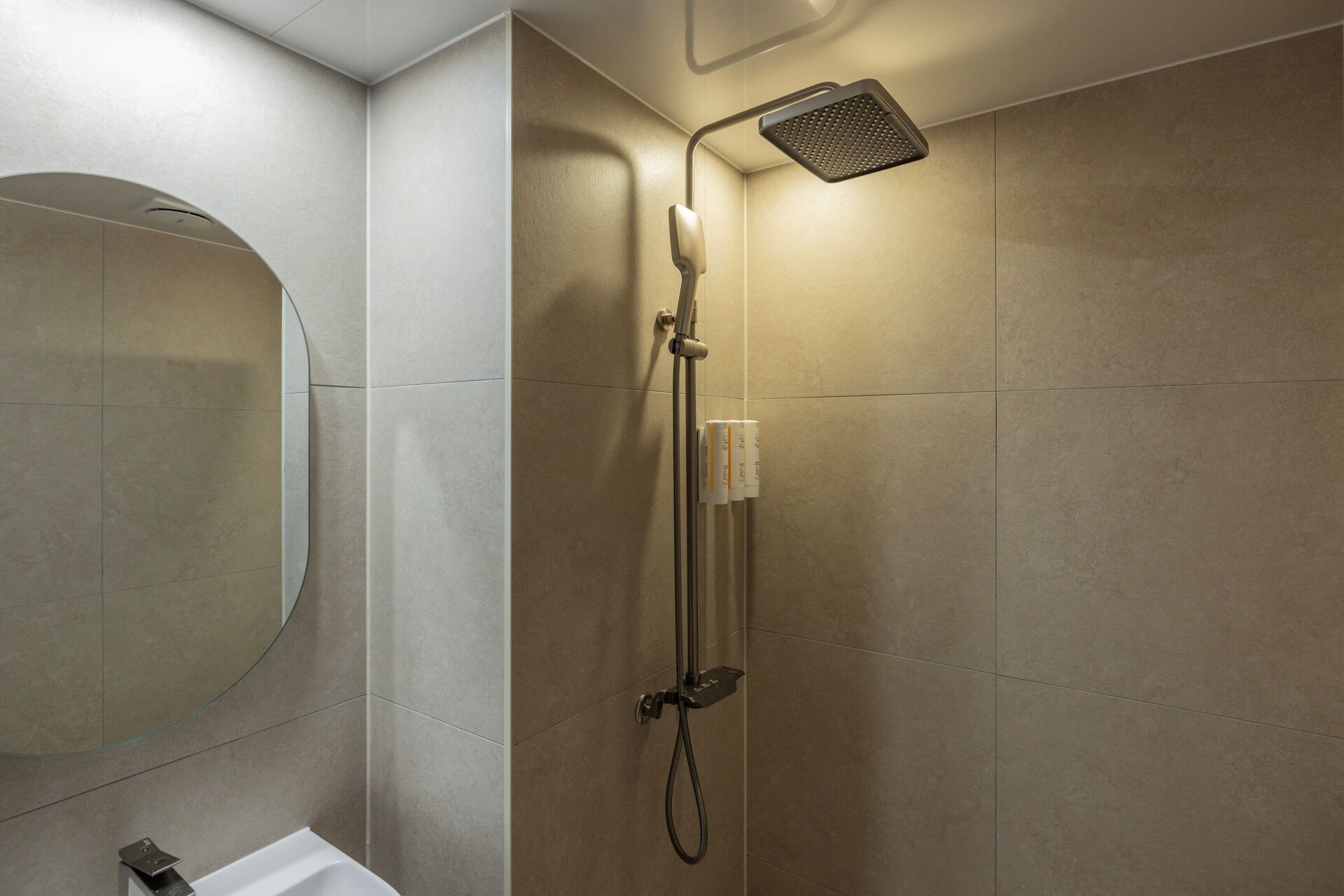 Un baño moderno con ducha, inodoro y un espejo grande.