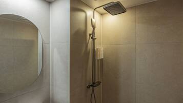 Un baño moderno con ducha, inodoro y un espejo grande.