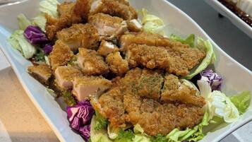 A rectangular white plate with a salad containing lettuce, purple cabbage, and breaded chicken pieces.