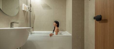 A bathroom with a freestanding bathtub, a sink, and a mirror.