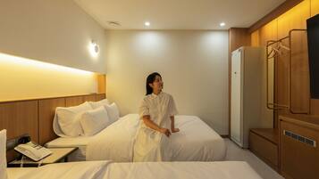 A hotel room with two beds, a bedside telephone, a wardrobe, and a mirror.