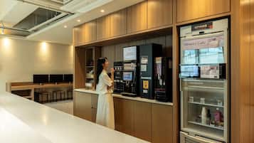 Un moderno vestíbulo de hotel con una larga recepción, un cartel de circuito cerrado de televisión y un refrigerador de cafetería de postres.