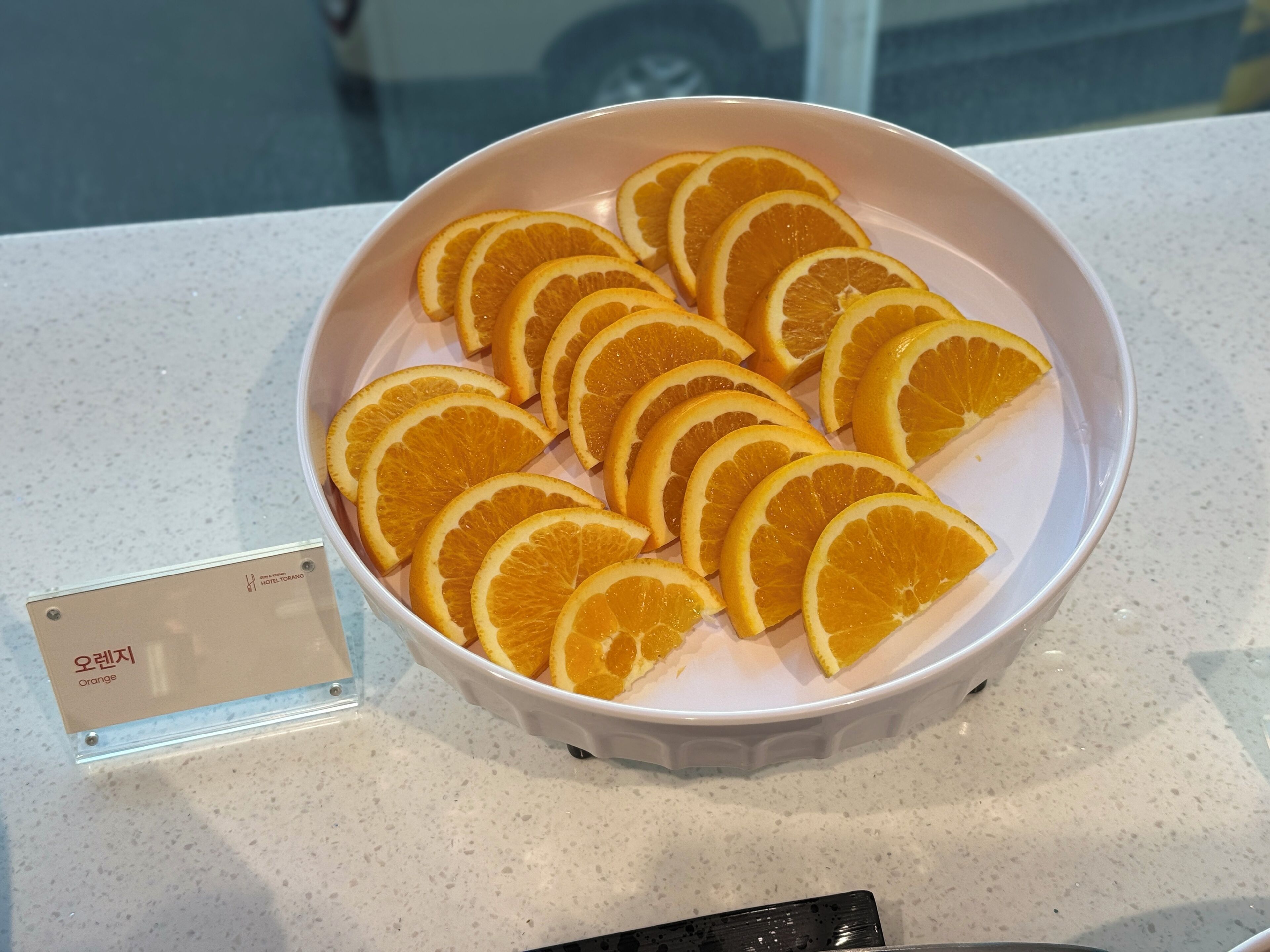 Un tazón blanco con rodajas de naranja sobre una encimera.