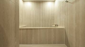 Een moderne douche met een minimalistisch ontwerp, met één kraan en een effen, lichtgekleurde vloer.