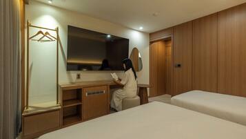 Una habitación de hotel con cama, escritorio, espejo y armario.