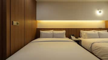 A hotel room with two beds, a bedside table with a phone, and a wall-mounted light fixture.