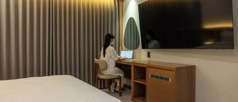 Una habitación de hotel con cama, escritorio y espejo.