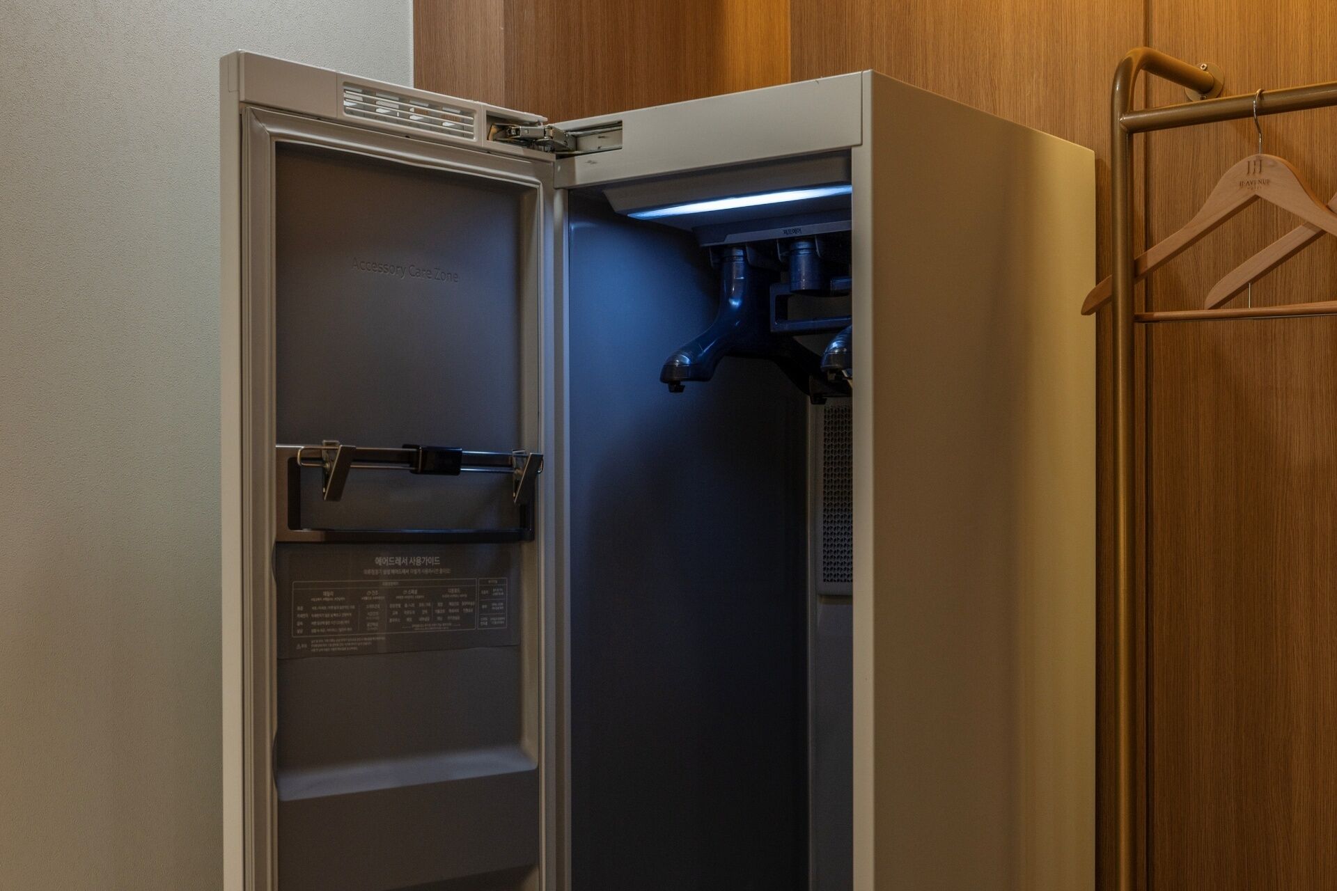 Ein Hotelzimmer mit Minibar, Holzschrank und Kleiderhaken.