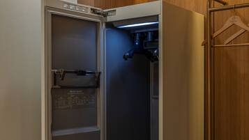 Ein Hotelzimmer mit Minibar, Holzschrank und Kleiderhaken.