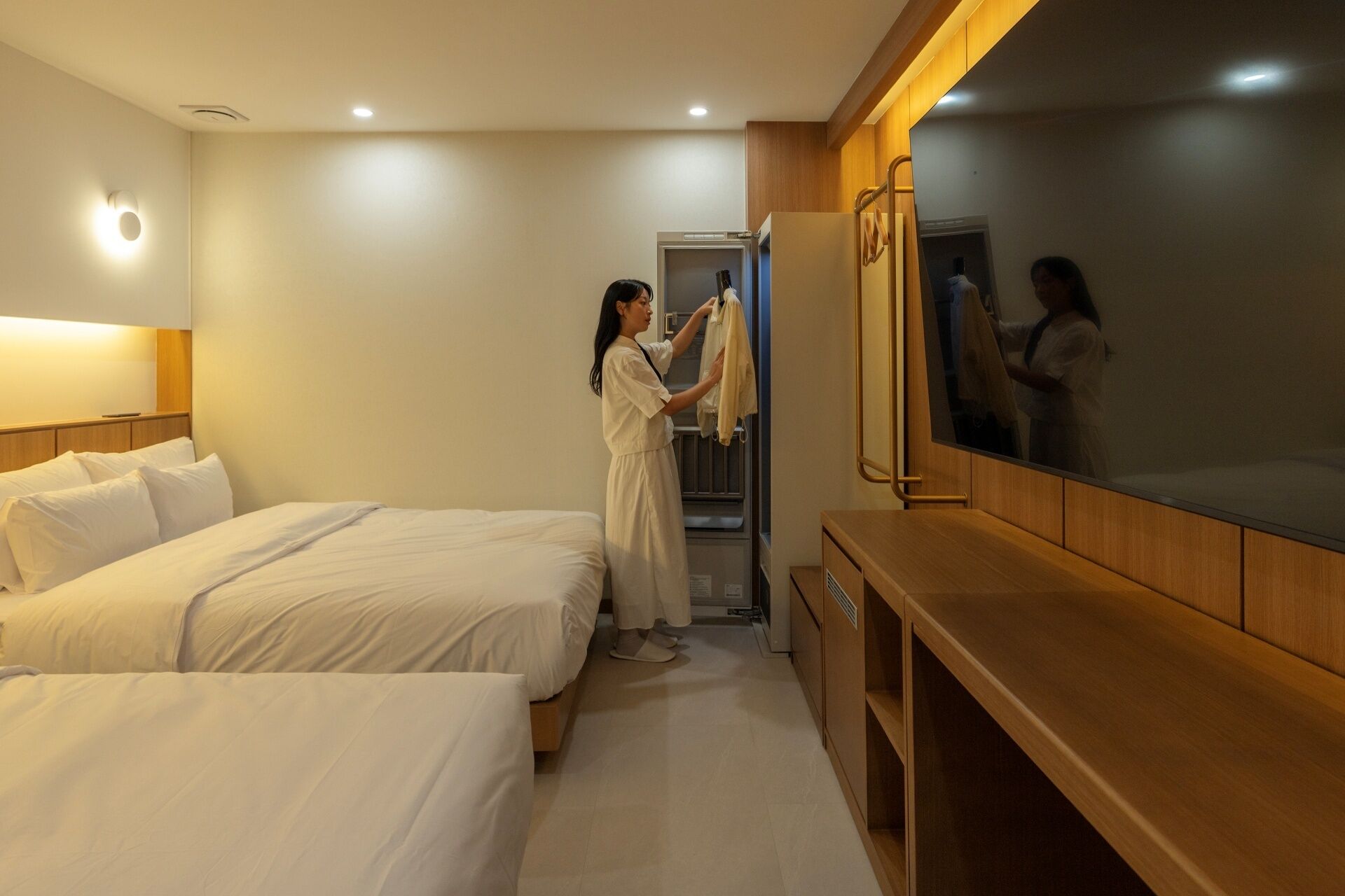 A hotel room with two beds, a wooden vanity, and a mirror.