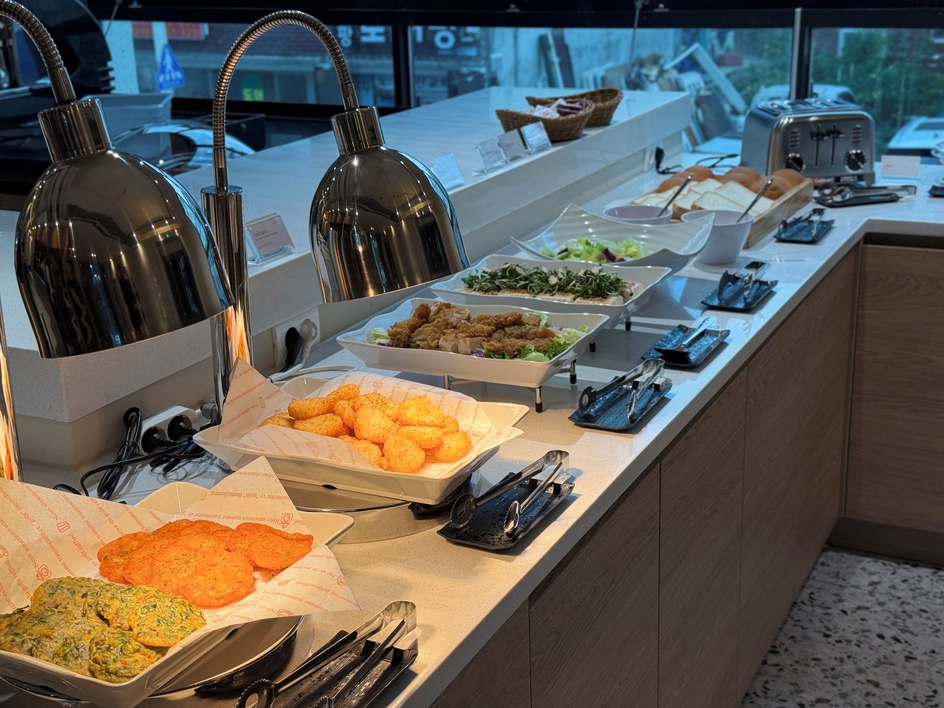 Un buffet proposant une variété de plats, notamment des pommes de terre en forme de petits cubes, des salades et d’autres mets.