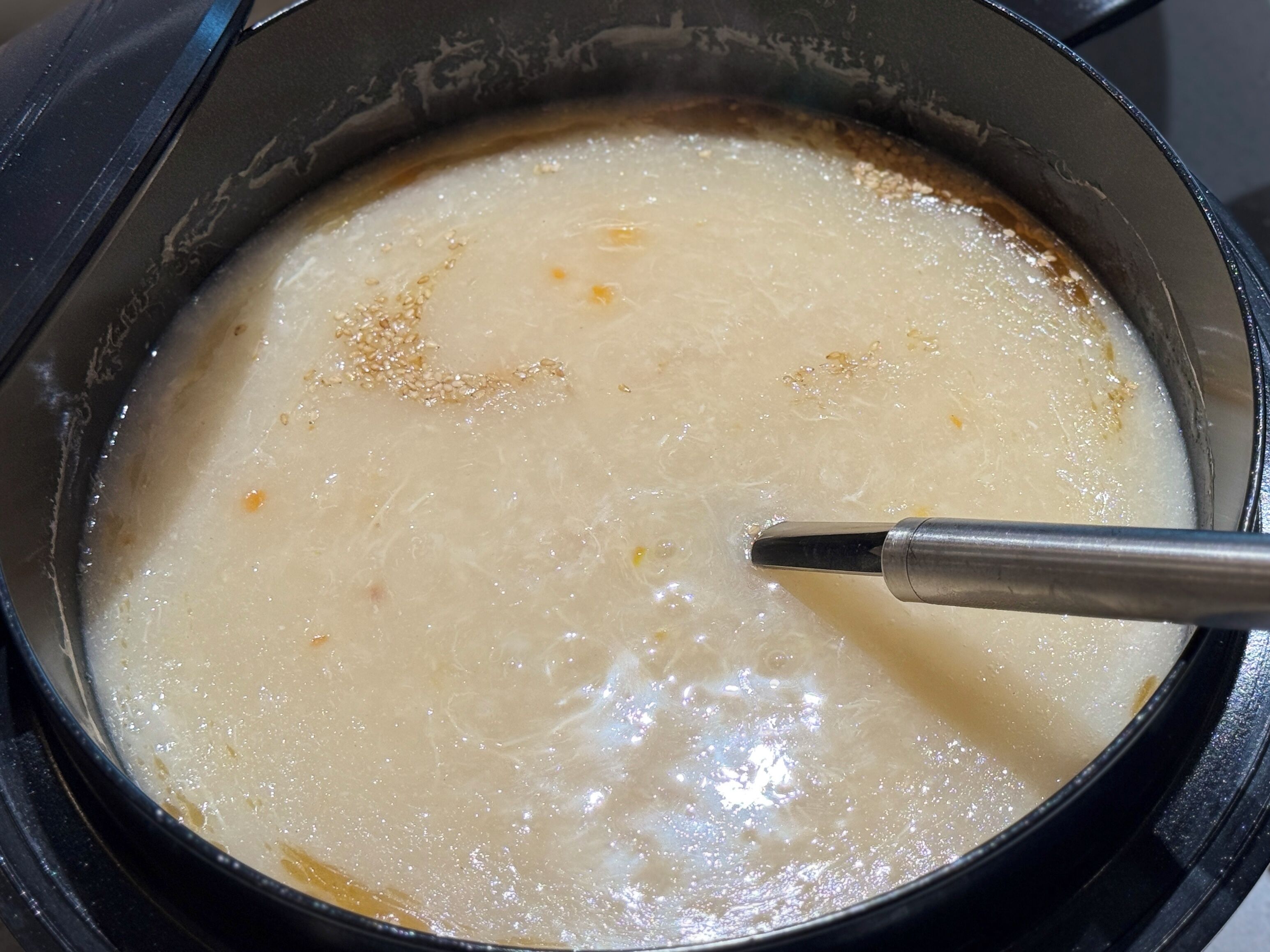 Una olla con una sustancia cremosa, posiblemente sopa o salsa, siendo removida con un utensilio.