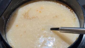 Una olla con una sustancia cremosa, posiblemente sopa o salsa, siendo removida con un utensilio.